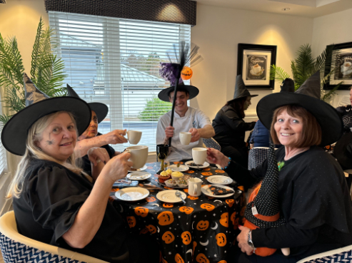 Residents, staff, and family members dressed in Halloween costumes, smiling