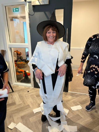 Residents, staff, and family members dressed in Halloween costumes, smiling