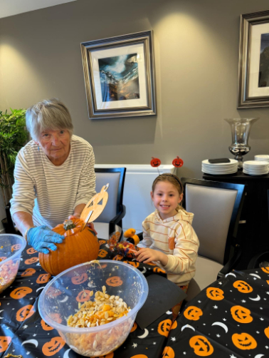 Residents, staff, and family members dressed in Halloween costumes, smiling