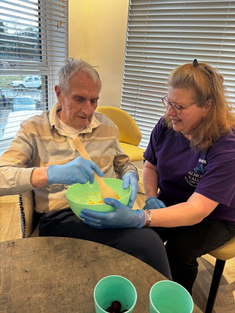 staff helping resident stir batter