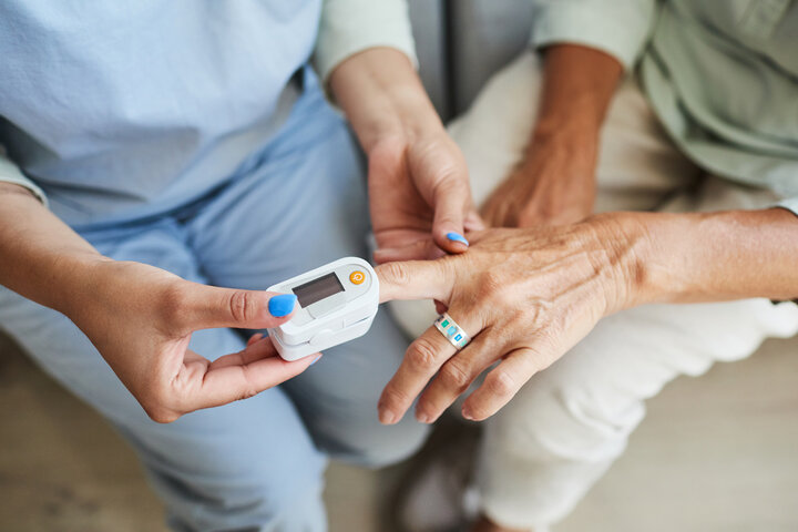 Close up of unrecognizable nurse measuring oxygen saturation of senior woman in retirement home