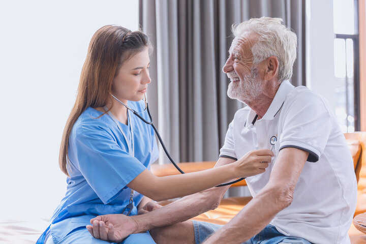 nurse checking residents heart rate on a bed 